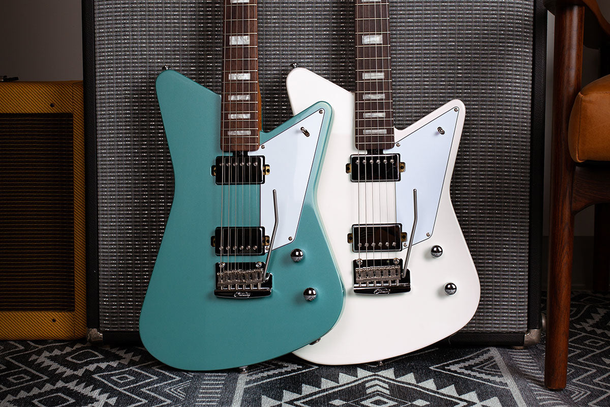 Mariposa guitars in Dorado Green and Imperial White resting against an amp.