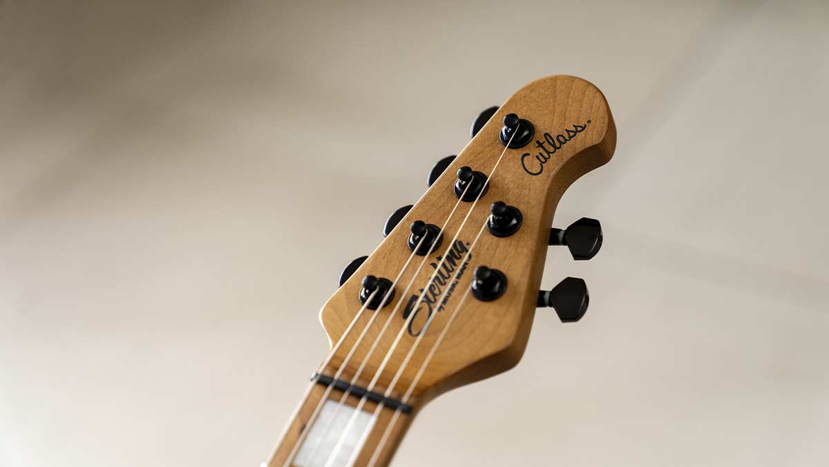 Closeup of an electric guitar with black tuning pegs