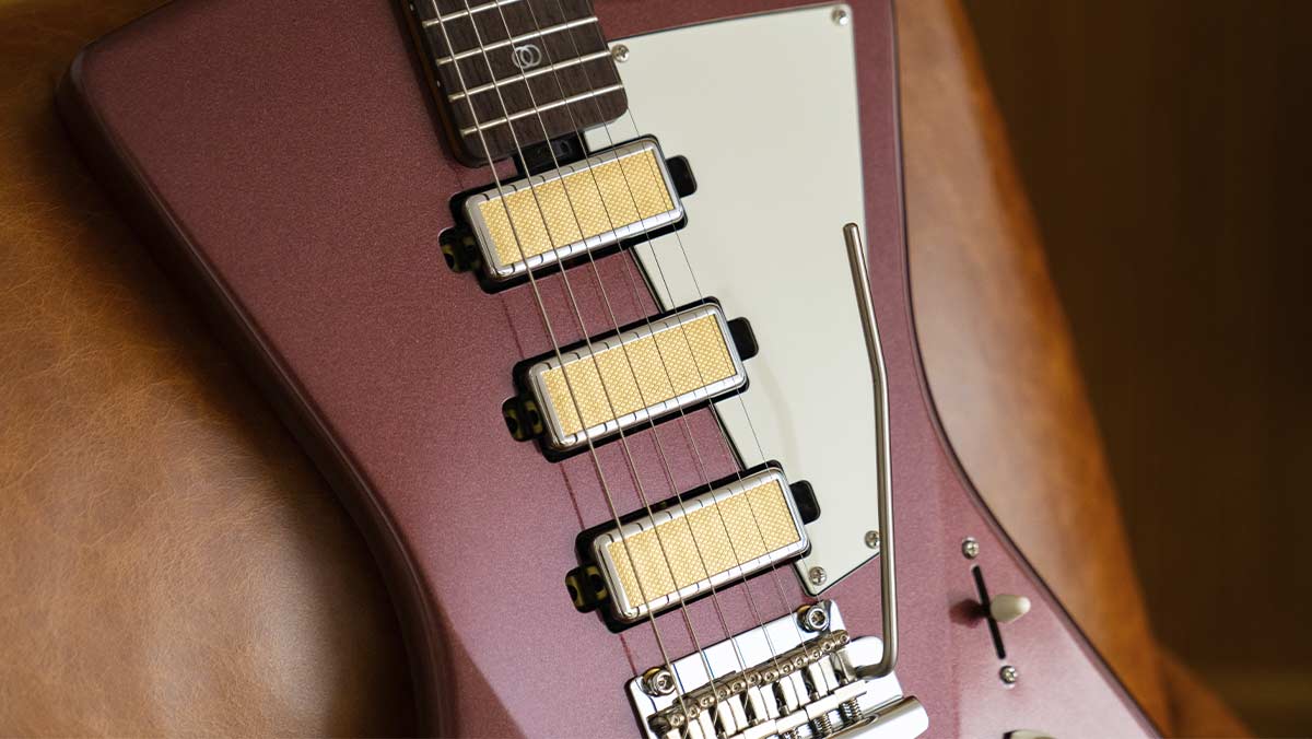 Closeup of a burgundy electric guitar with gold foil humbuckers