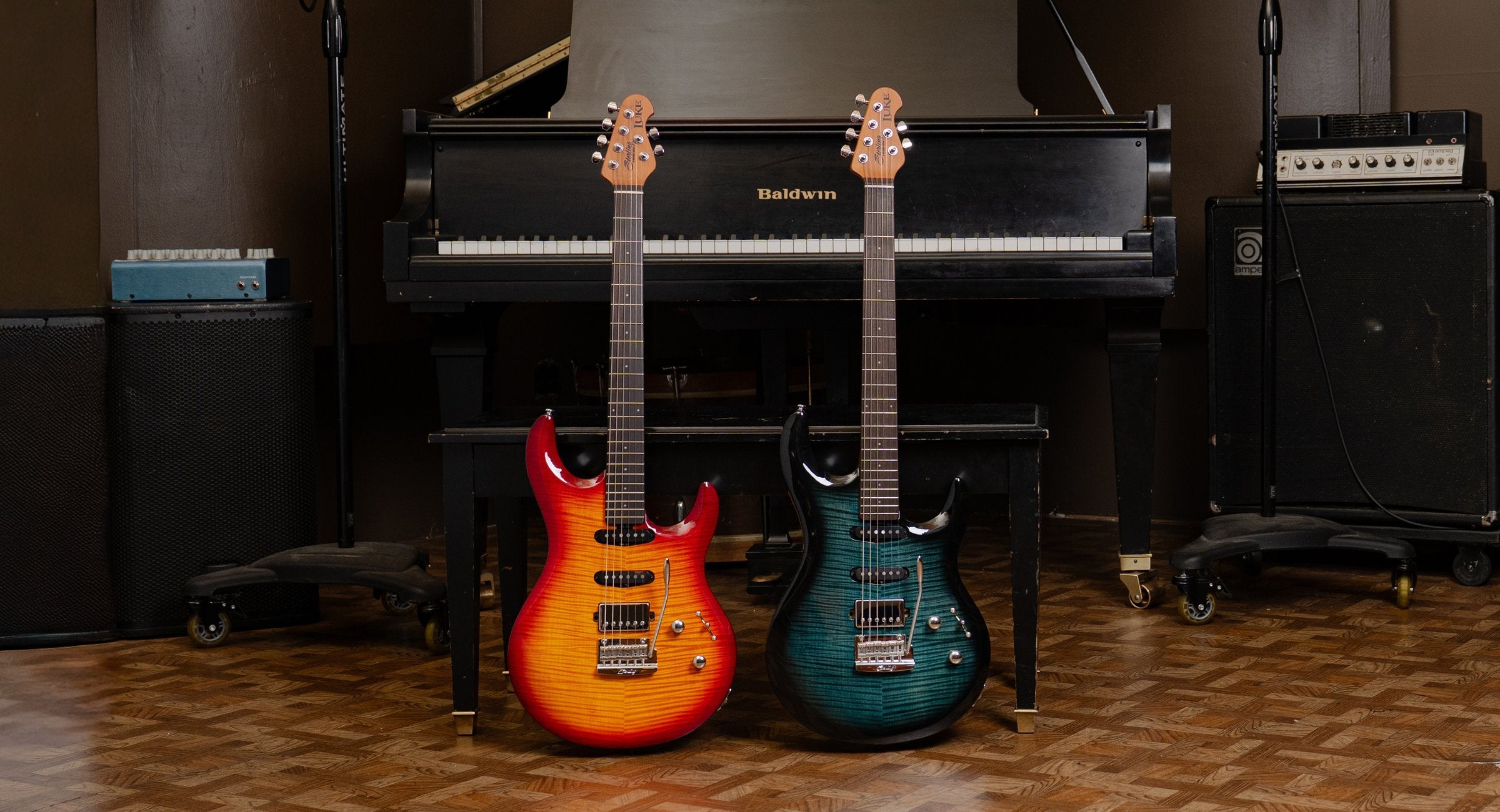 Two electric guitars in front of a piano on a wooden floor.